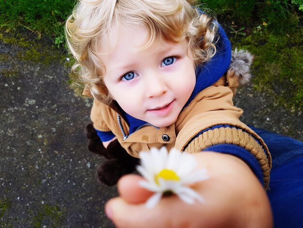 Foto retrato de un niño lindo sosteniendo una margarita