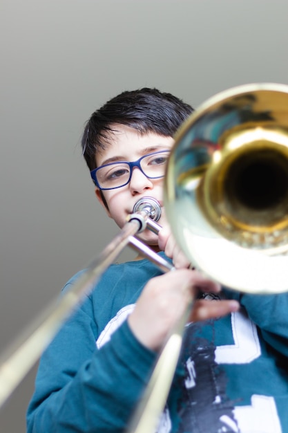 Foto retrato de un niño lindo tocando la trompeta contra la pared