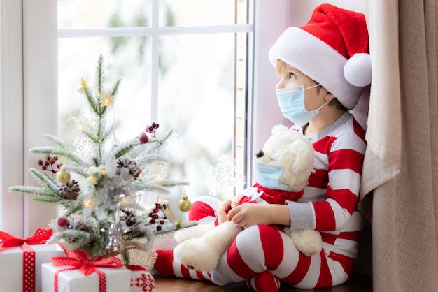 Retrato de niño con máscara médica vacaciones de Navidad durante el concepto de pandemia de coronavirus covid19