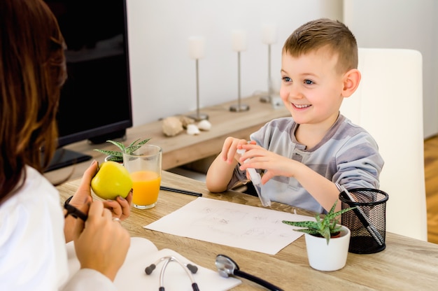 Retrato de un niño masculino lindo que consigue la fruta de la manzana del doctor