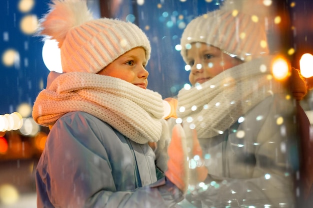 Retrato niño mirando y soñando en escaparates navideños en el tradicional mercado navideño navidad