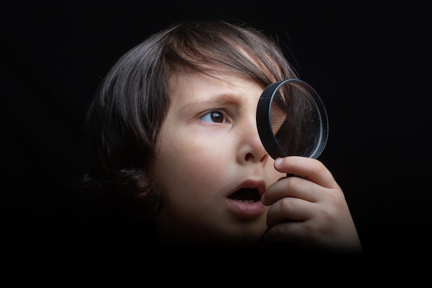 Retrato de un niño mirando a través de la lupa