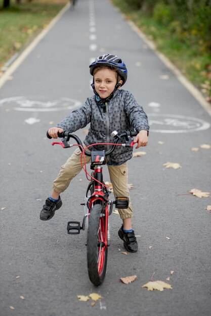 Foto retrato de un niño montando una bicicleta en la carretera