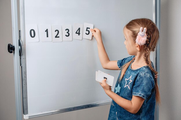 Retrato de niño muy hermoso sharming arreglando números en el orden correcto. Niño adorable que sostiene una tarjeta con el número 5. Concepto de matemáticas. foto con ruido