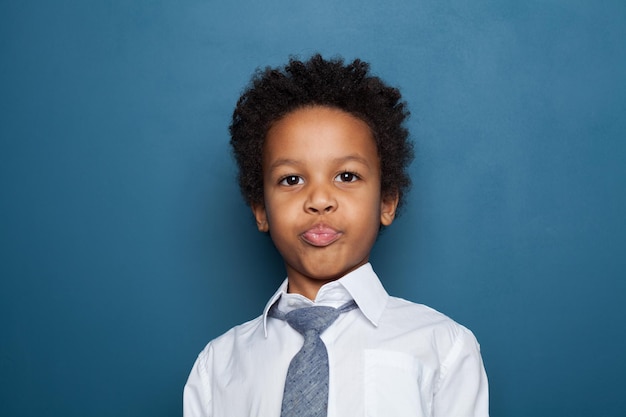 Retrato de un niño negro gracioso sobre un fondo azul