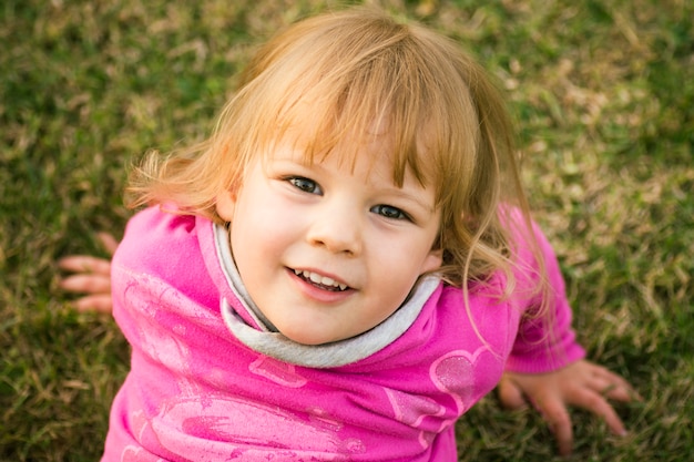 Retrato de niño de niña linda de pelo rubio al aire libre en el césped