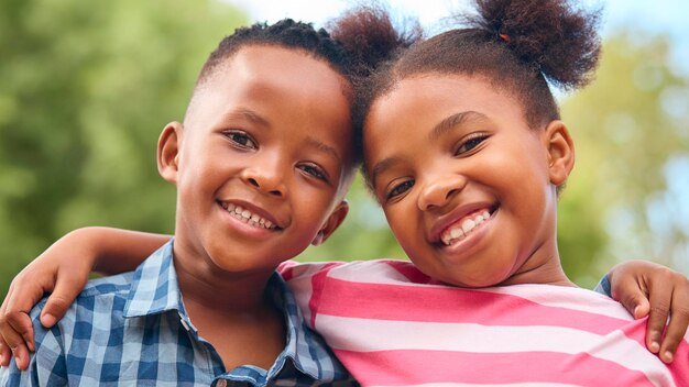 Retrato de un niño y una niña sonrientes y riendo abrazándose al aire libre en el campo o en el jardín