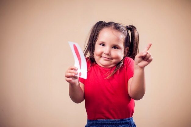 Retrato de niño niña con tarjeta con signo de exclamación. Concepto de niños y educación