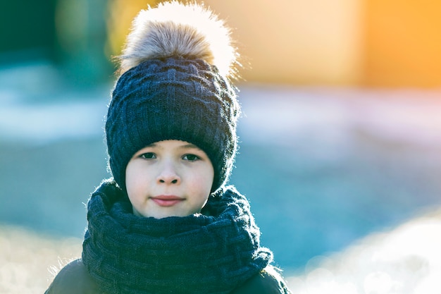 Retrato de niño niño con sombrero y bufanda al aire libre en un día soleado de invierno