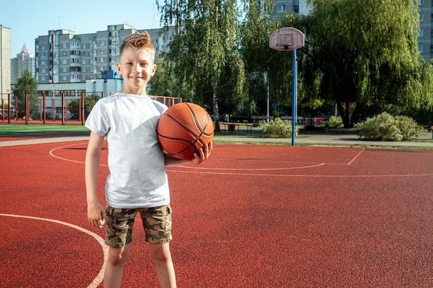 Retrato de un niño con una pelota de baloncesto en una cancha de baloncesto