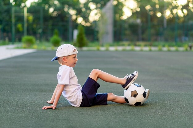 Retrato de un niño con una pelota de fútbol en sus manos en el campo de fútbol