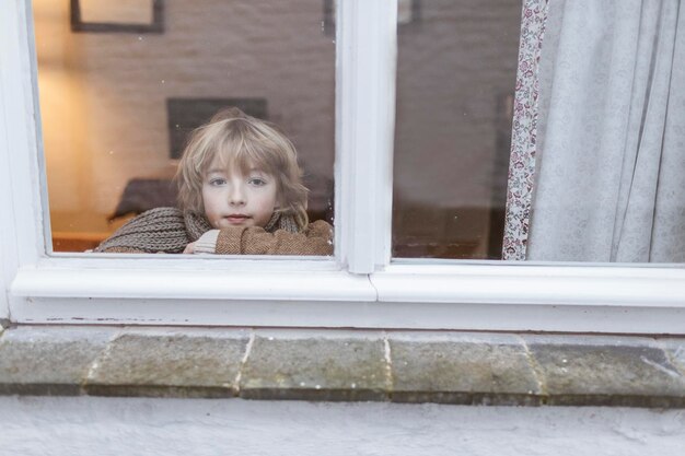 Retrato de niño pensativo mirando por la ventana