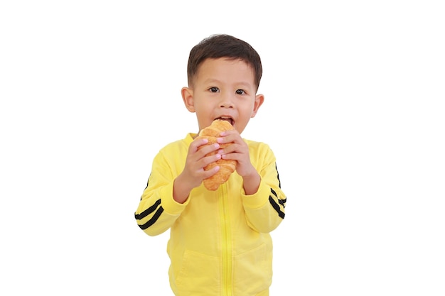 Retrato de niño pequeño asiático comiendo croissant