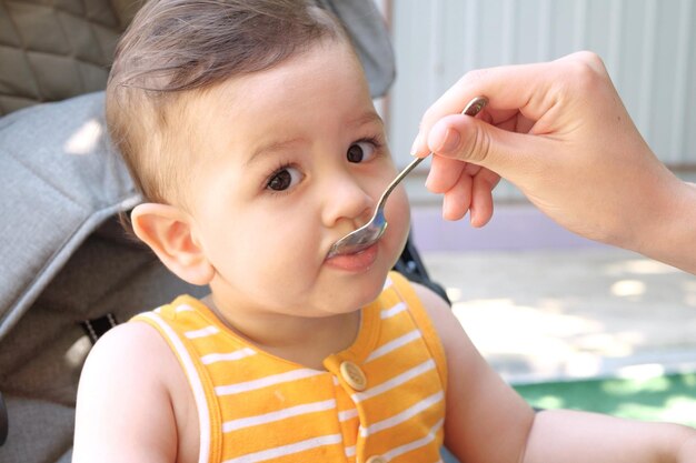 Retrato de niño pequeño comiendo comida Bebé con una cuchara en la silla de alimentación Lindo bebé comiendo su primera comida