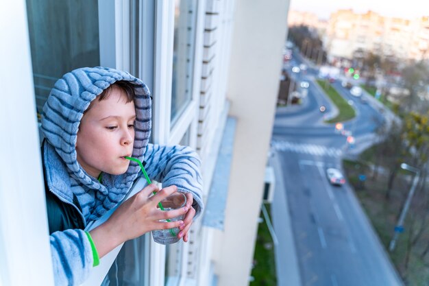 Retrato de niño pequeño encantador divertido que sopla pompas de jabón desde el balcón. Niño jugando en casa.