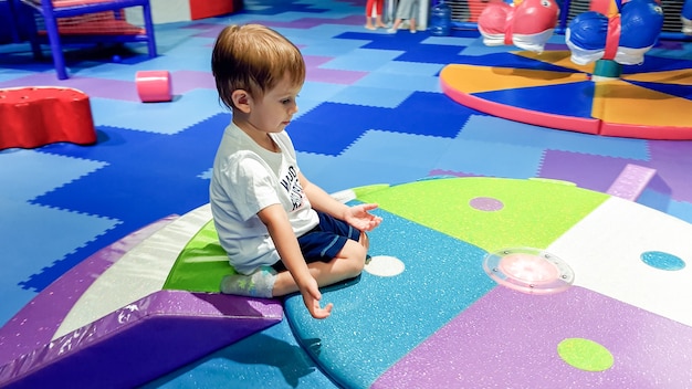 Retrato de niño pequeño gateando y jugando en los coloridos niños palyground cubiertos con suaves esteras en el centro comercial