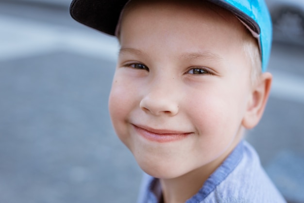 Retrato de un niño pequeño con una gorra azul en el primer plano de la calle un niño con cabello rubio y ojos azules ...