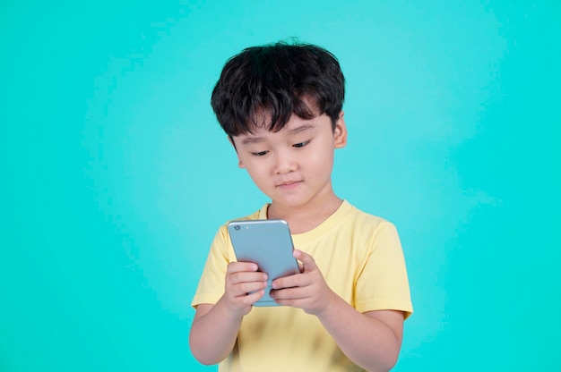 Retrato de un niño pequeño y guapo asiático usando un teléfono inteligente i