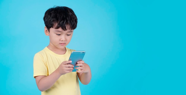 Retrato de un niño pequeño y guapo asiático usando un teléfono inteligente i