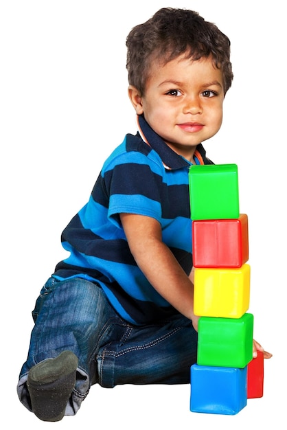 Retrato de un niño pequeño y guapo sentado cerca de bloques de juguete