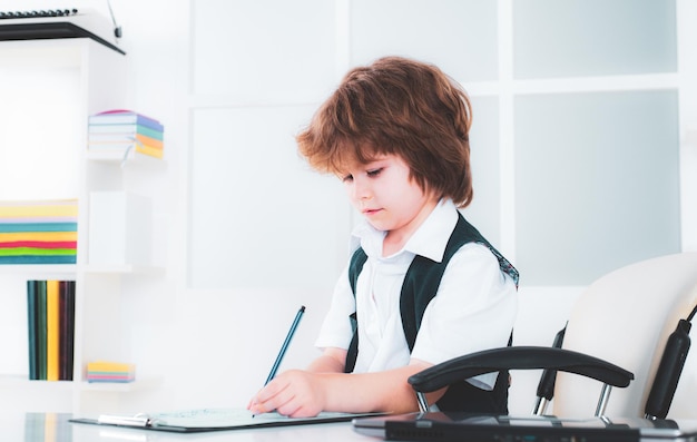 Retrato de niño pequeño hombre sentado en su escritorio en la oficina niño empresario en su oficina des