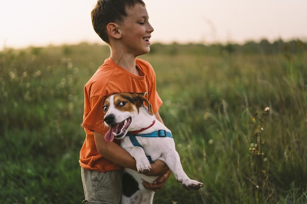 Retrato de un niño pequeño jugando con su perro Jack Russell en el parque