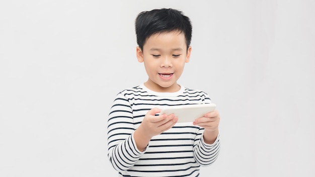 Retrato de un niño pequeño lindo divertido jugando en el teléfono inteligente aislado sobre fondo blanco.