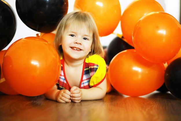 Retrato de un niño pequeño tirado en el suelo en una habitación decorada con globos. Concepto de infancia feliz.