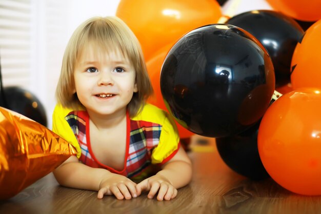 Retrato de un niño pequeño tirado en el suelo en una habitación decorada con globos. Concepto de infancia feliz.