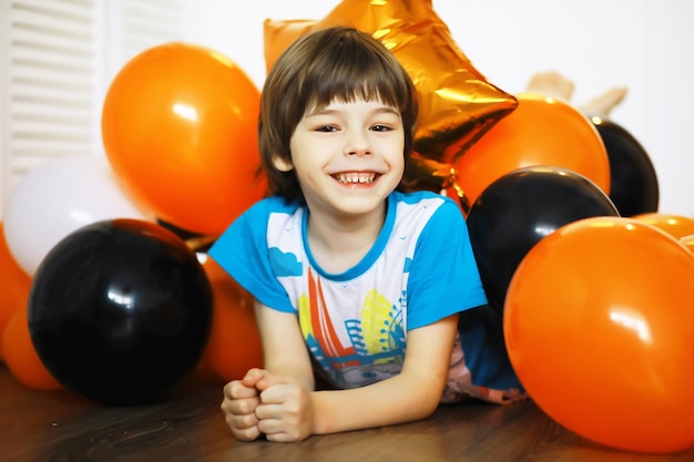 Retrato de un niño pequeño tirado en el suelo en una habitación decorada con globos. Concepto de infancia feliz.