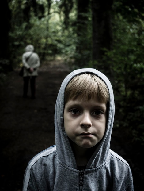 Retrato de un niño de pie en un camino de tierra en el bosque