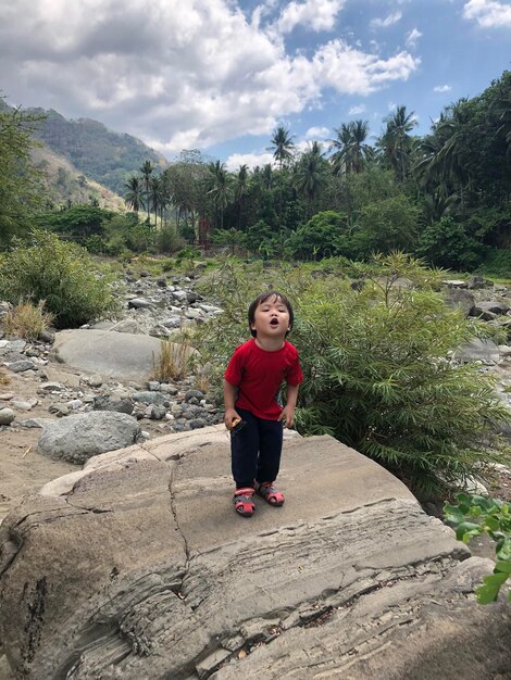 Foto retrato de un niño de pie en una roca contra el cielo