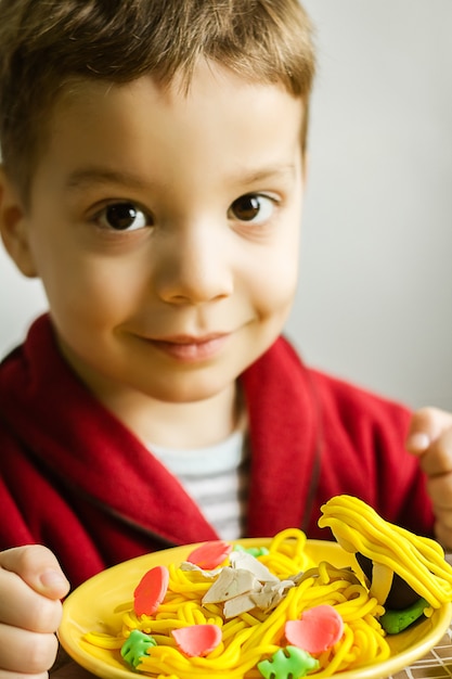 Retrato de niño con plato de espaguetis de plastilina