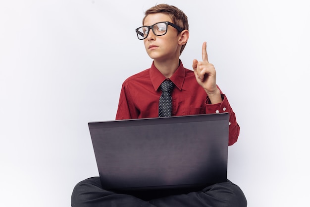 Retrato de un niño positivo y emocional posando con una computadora portátil