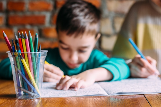 Retrato de un niño preescolar feliz lindo en casa o en un café dibuja