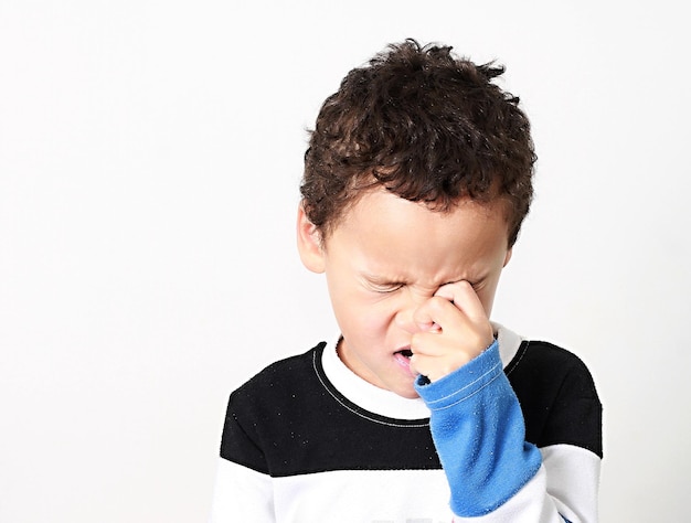 Foto retrato de un niño que mira hacia otro lado contra un fondo blanco