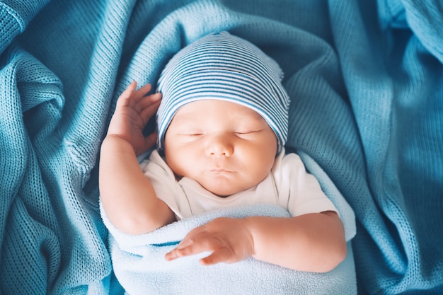 Retrato de niño recién nacido niño de una semana durmiendo plácidamente en la cuna en el fondo de tela