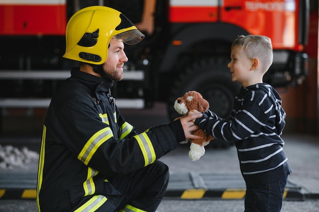 Retrato de un niño rescatado con un bombero parado cerca de un camión de bomberos