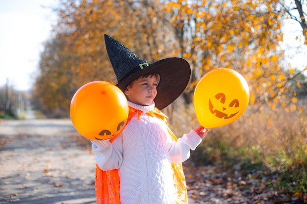 Retrato de un niño con ropa de Halloween con globos de calabaza en la calle Una fiesta tradicional 31 de octubre