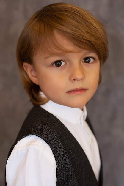 retrato de un niño rubio con una camisa blanca y grandes ojos marrones