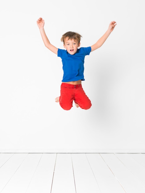 Foto retrato de un niño saltando contra un fondo blanco