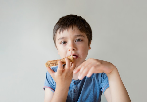 Foto retrato niño sano comiendo miel en tostadas para su desayuno antes de ir a la escuela, niño niño feliz comiendo mantequilla en pan por la mañana, concepto de comida sana para niños
