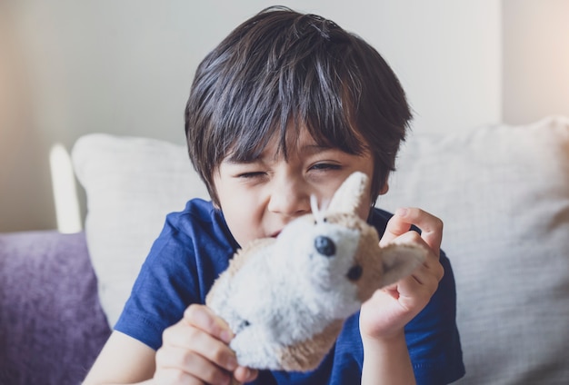 Retrato de niño sano jugando con juguete para perros con cara divertida, tiro sincero niño lindo niño relajante quedarse en casa durante el encierro codicioso Concepto de niños positivos, distanciamiento social