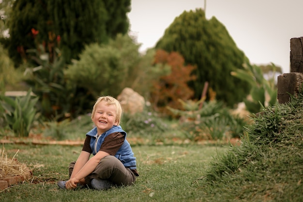 Retrato de un niño sentado en un bonito jardín