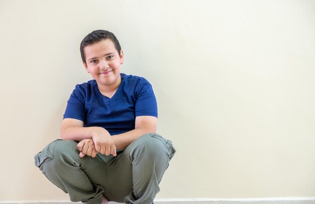 Retrato de un niño sentado en el pasillo de la escuela