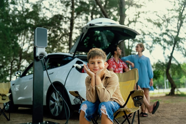 Retrato de un niño sentado en una silla de campamento con la familia perpetua