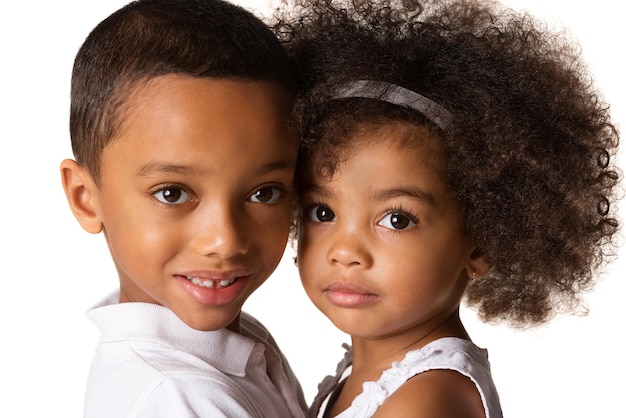 Foto retrato de un niño sonriente abrazando a su hermana contra un fondo blanco