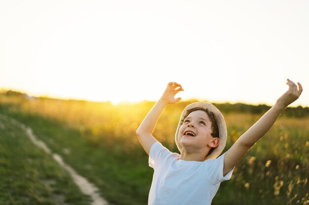 Retrato de un niño sonriente con una camiseta blanca levantando las manos y jugando