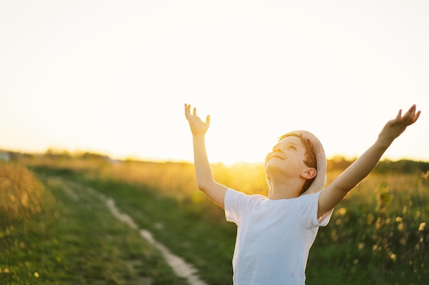 Retrato de un niño sonriente con una camiseta blanca levantando las manos y jugando