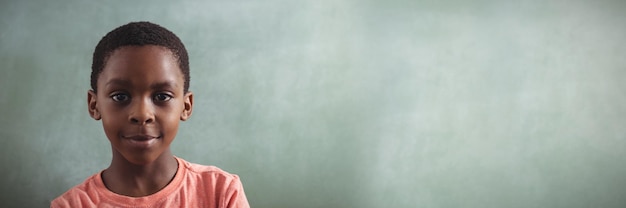 Retrato de niño sonriente contra greenboard en blanco en el aula